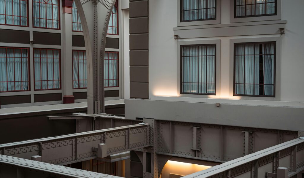 Interior view of a modern building showcasing large steel beams and windows.